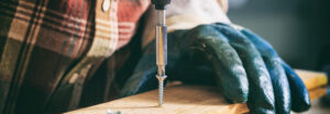Man using screwdriver to drill plank of wood