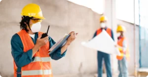 Safety lead uses radio and clipboard to coordinate site activity, reflecting proactive leadership and communication.