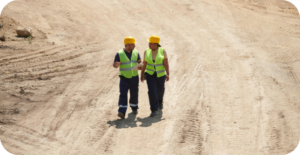 Safety team walking on site wearing helmets and vests.
