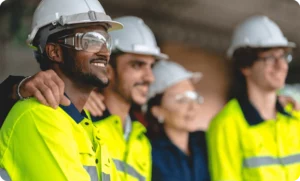 Coworkers collaborating and smiling on a job site, representing inclusive safety culture built through trust, teamwork, and shared responsibility—not top-down enforcement.