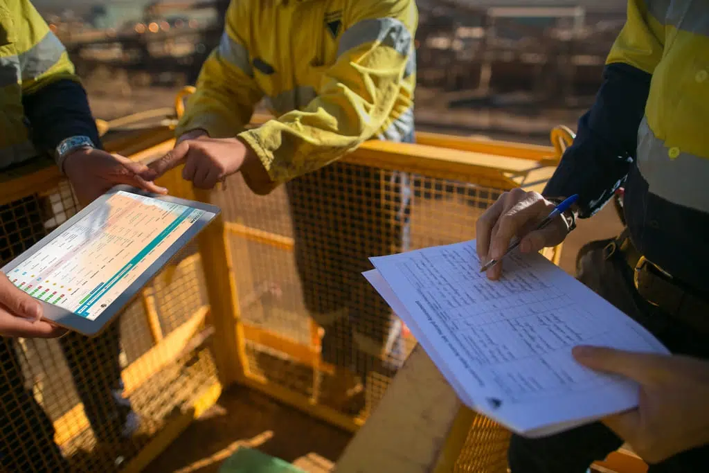 Workers reviewing safety checklists digitally and on paper, supporting both compliance and field readiness.