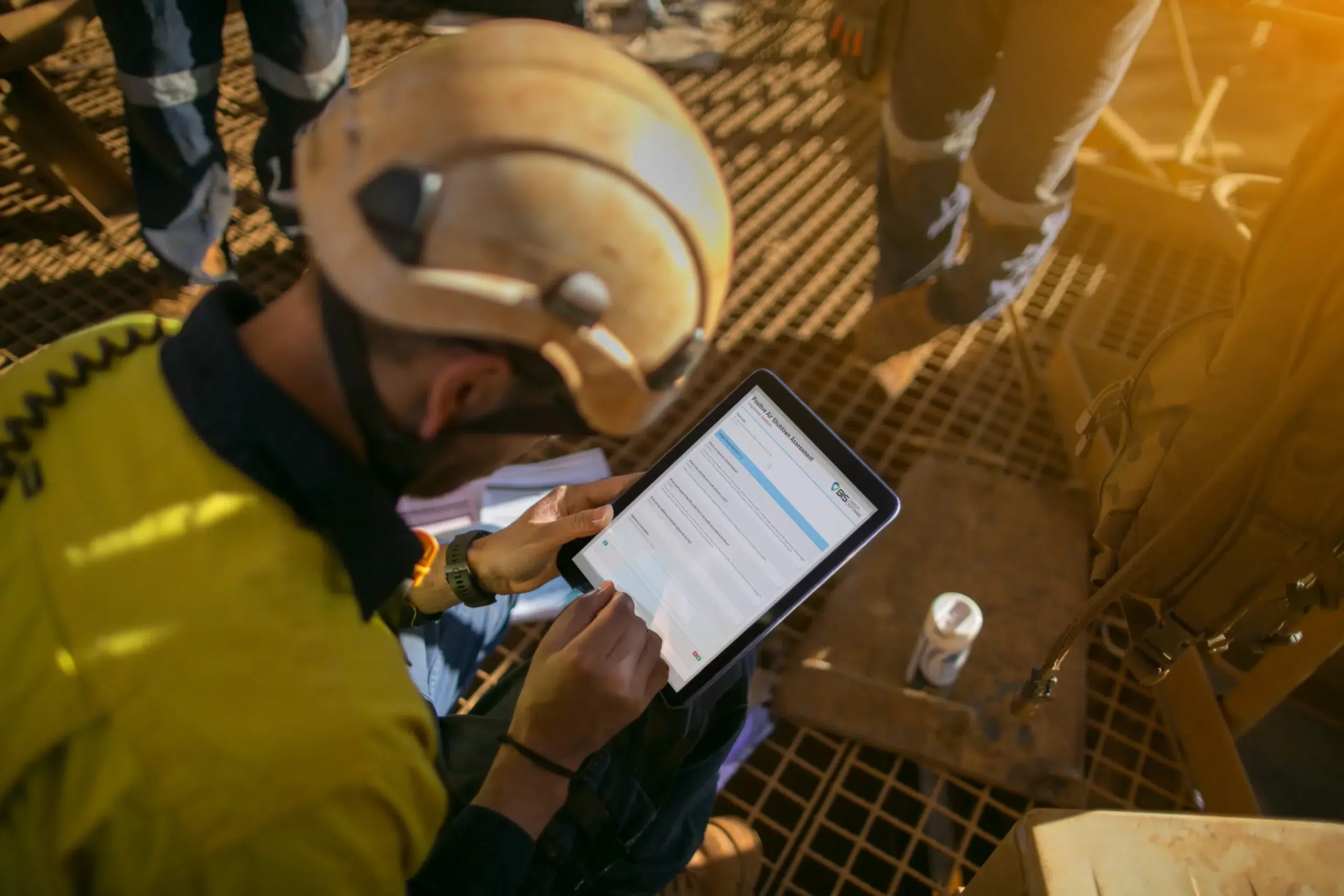 Field crew member filling out a mobile FLHA tech assessment on a tablet during worksite operations.