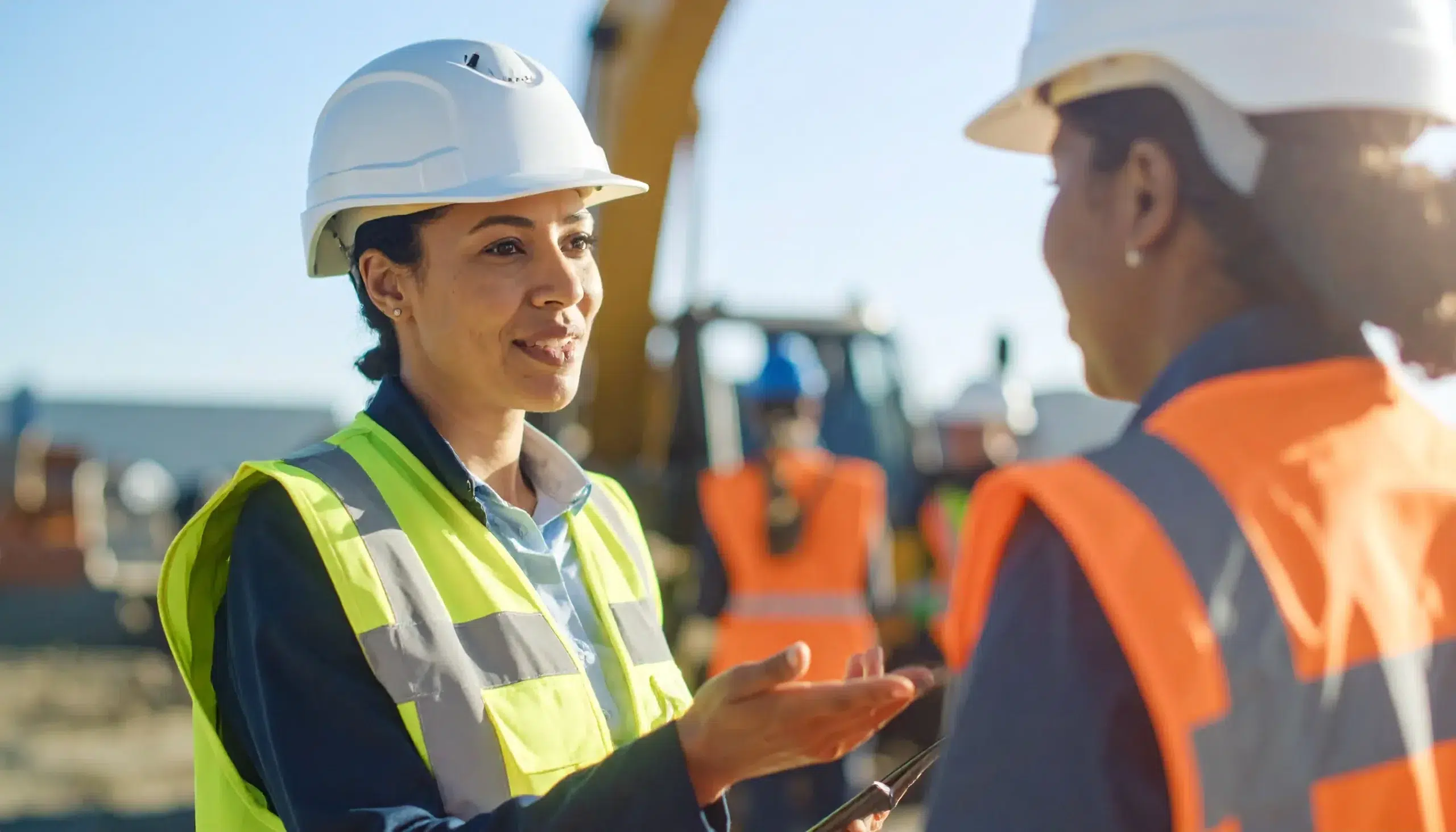 Two workers having an open safety conversation during onboarding at a construction site.