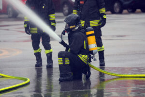 Firefighter with an oxygen tank and mask spraying a large amount of water during an emergency