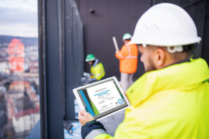Worker in safety gear using a tablet to access training records during construction.