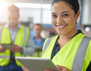 Construction worker reviewing a digital FLHA solution using a tablet with her team members.