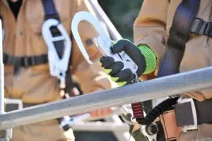 Canadian worker fastening safety harness to scaffolding for fall protection.