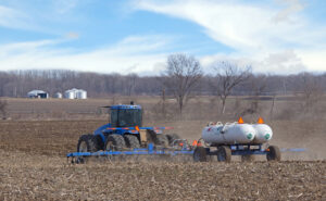 Farm tractor pulling twin NH₃ nurse tanks during field application, showing agricultural use of anhydrous ammonia.
