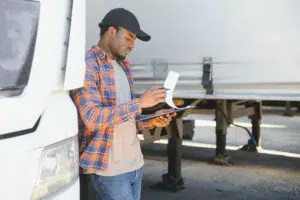 Commercial truck driver inspecting documents to ensure compliance with weight and dimension regulations.