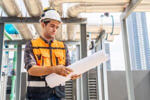Lone technician reviewing safety documents in an industrial environment, highlighting control measures.