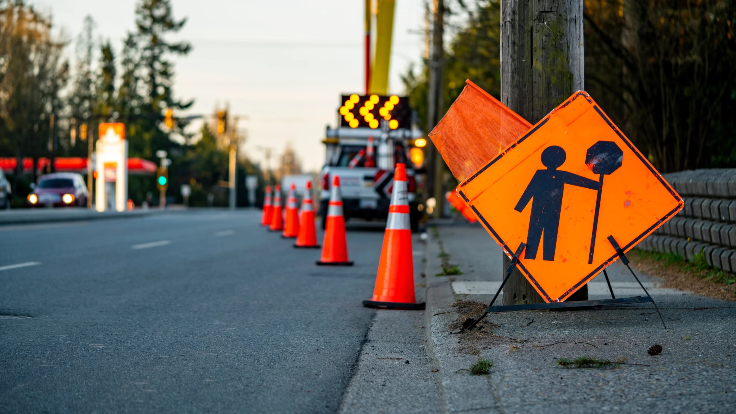 Vehicles navigating a coned corridor, emphasizing visibility and reduced speed in a work zone.