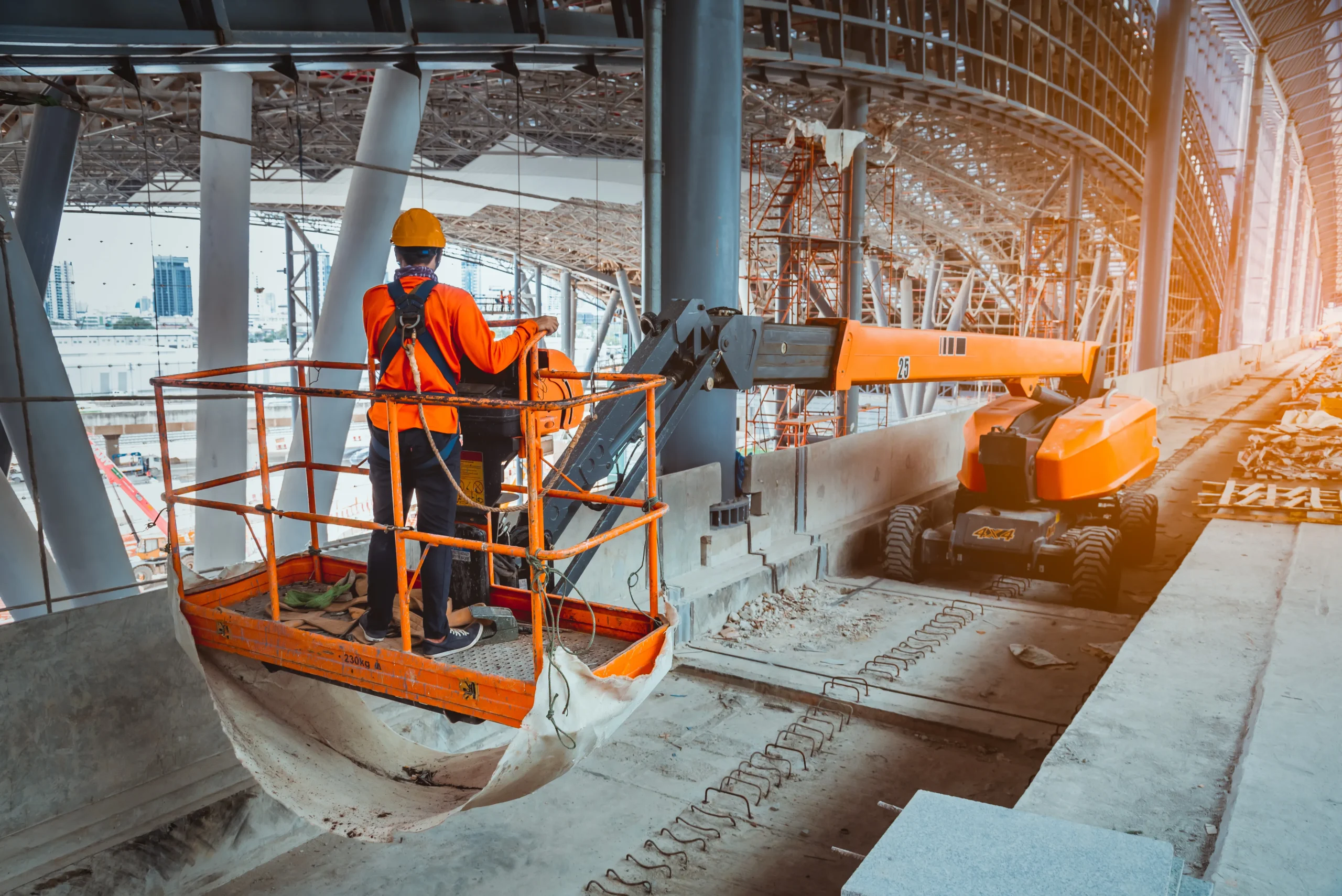 Worker using boom lift indoors with proper gear, demonstrating compliance during high-access tasks​.