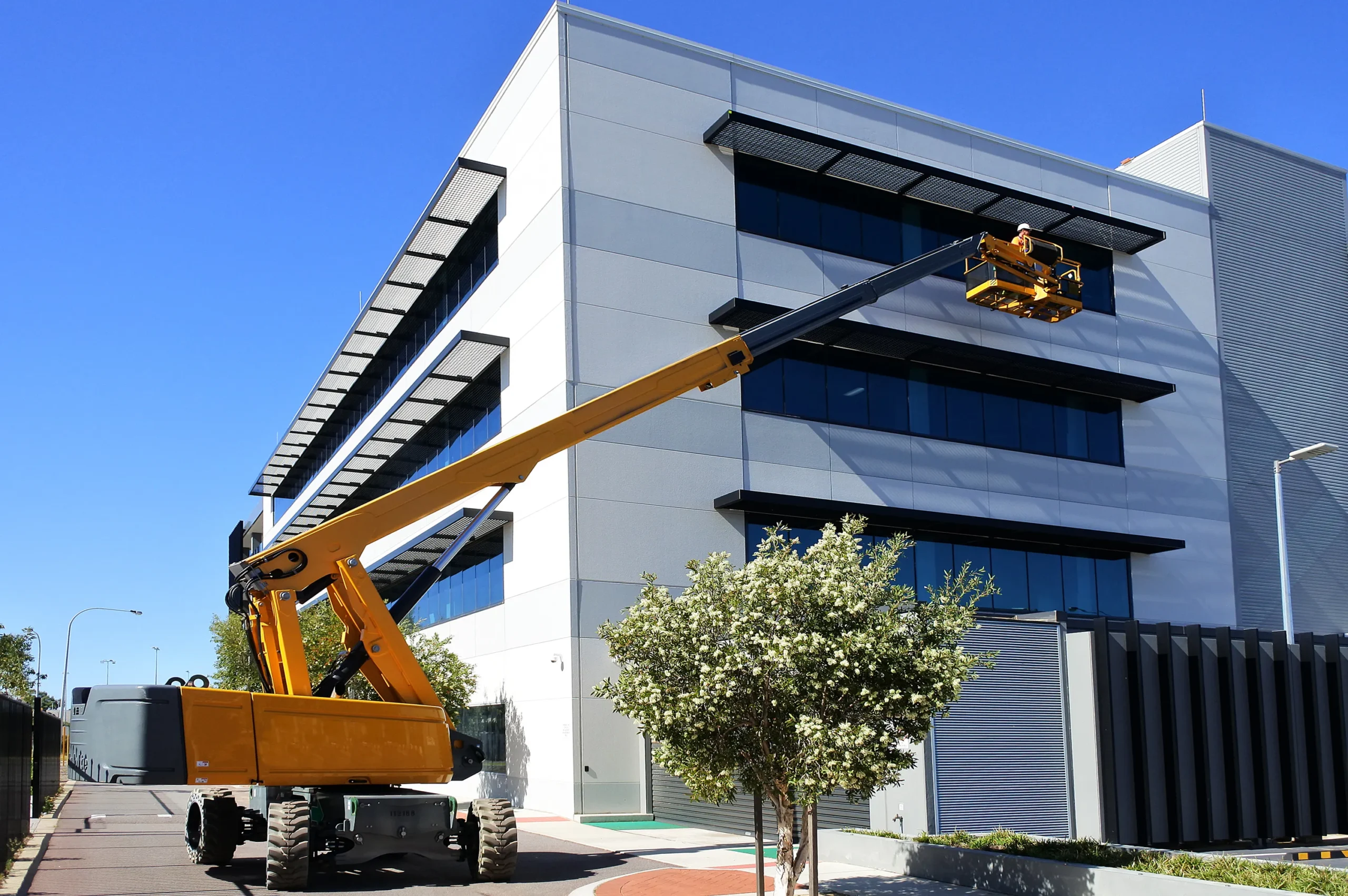 Boom lift raising worker for structural installation, emphasizing safe high-access operation​.