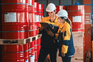 Safety professionals in hard hats reviewing chemical inventory for WHMIS compliance​.