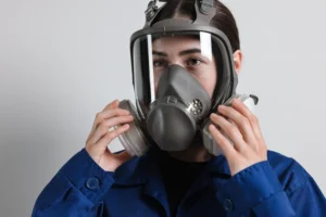 Safety worker inspecting and adjusting respirator mask for correct workplace fit and seal​