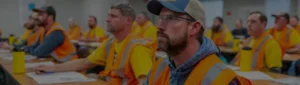 Workers in safety vests and yellow shirts attending classroom safety compliance training