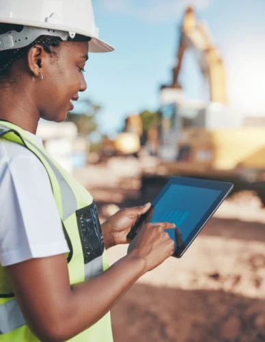 Construction worker using a tablet to check certifications, training status, and on-the-job competency results in real time.