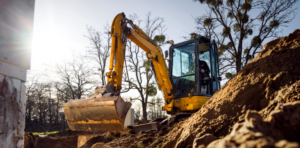 Mini excavator operator receiving safety instruction during hands-on mini excavator training on a construction site.