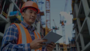 Construction worker using a tablet to manage digital safety inspections and site compliance.