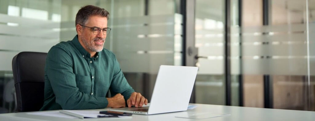 - BIS Safety Software Canada Smiling busy older professional business man working on laptop sitting at desk while taking a virtual proctored online course