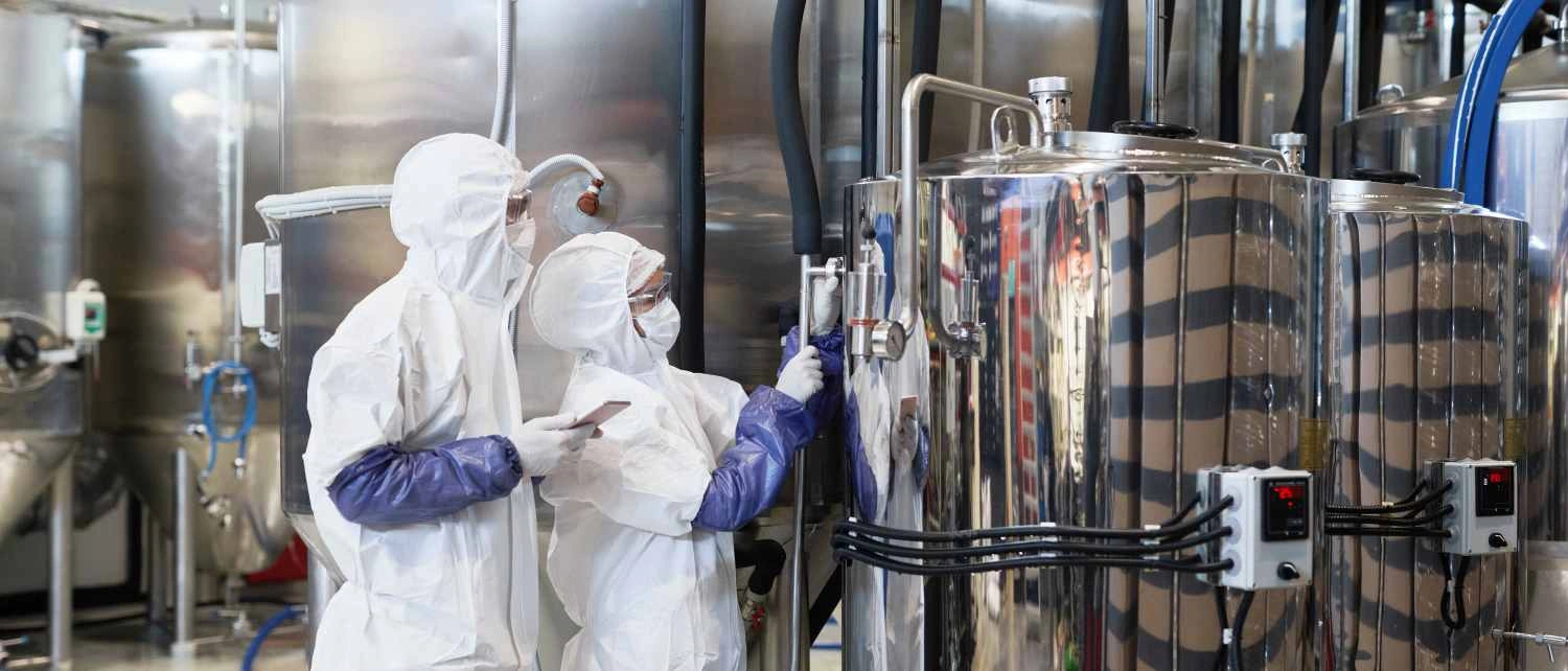 Wide angle view at two workers wearing protective suits while inspecting production at modern chemical plant, copy space
